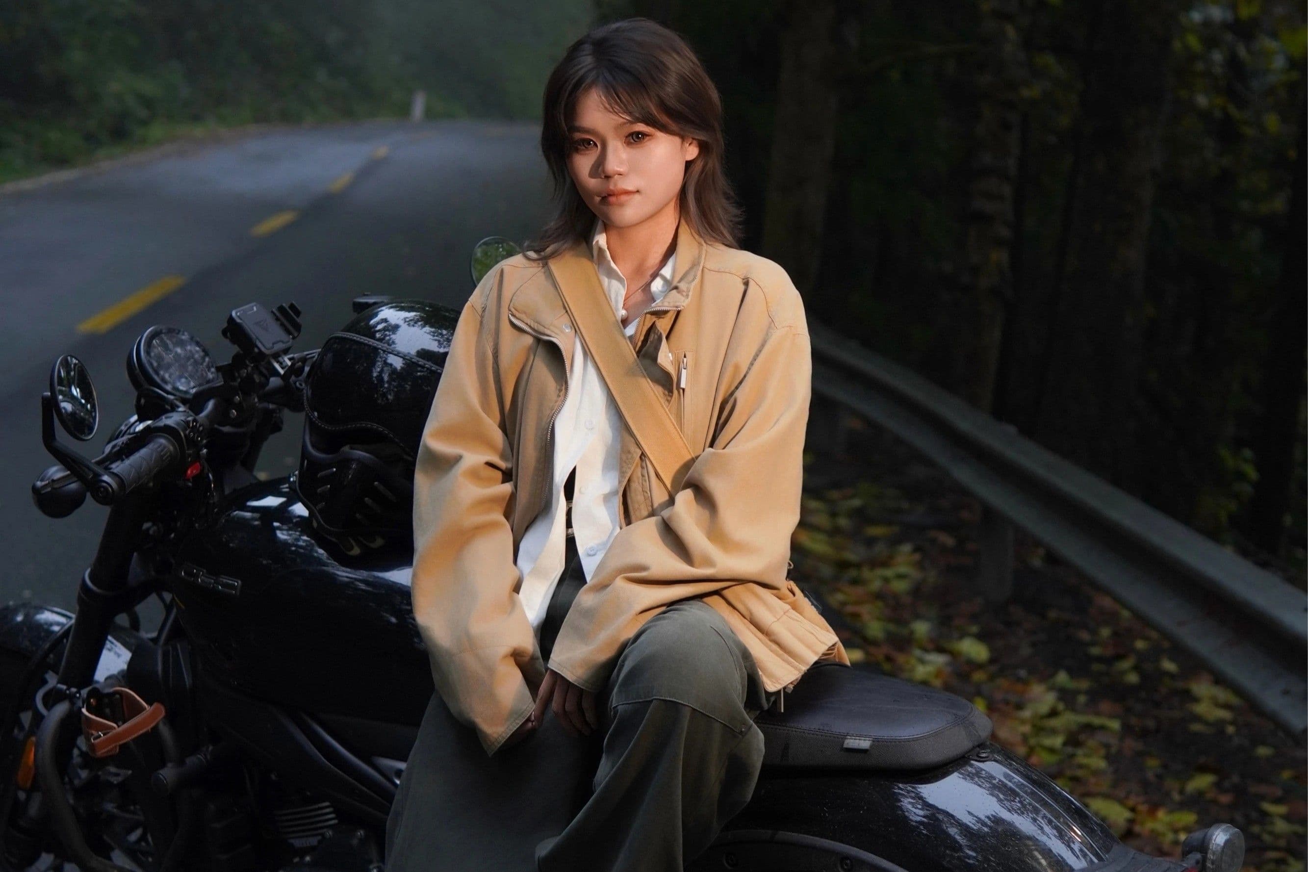 Woman in brown jacket sits on a black motorcycle on a misty, tree-lined road.