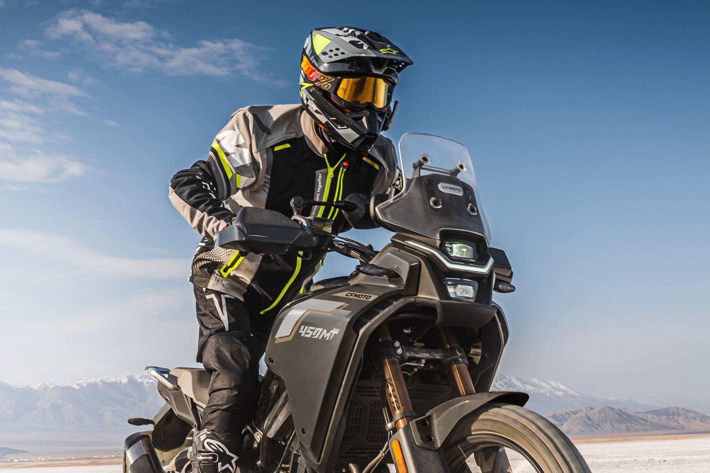 Rider in helmet and goggles on a black adventure motorcycle, riding towards the camera.